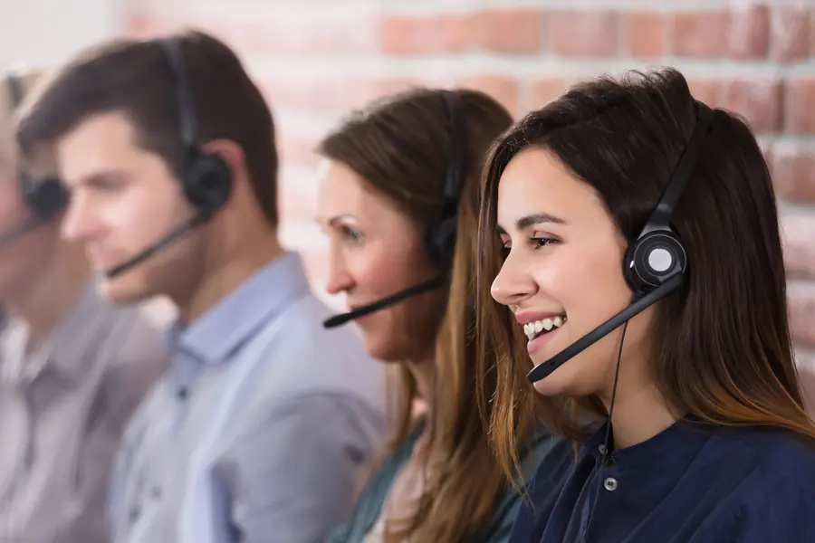Drei Mitarbeitende mit Headsets an ihren Arbeitsplätzen im Callcenter